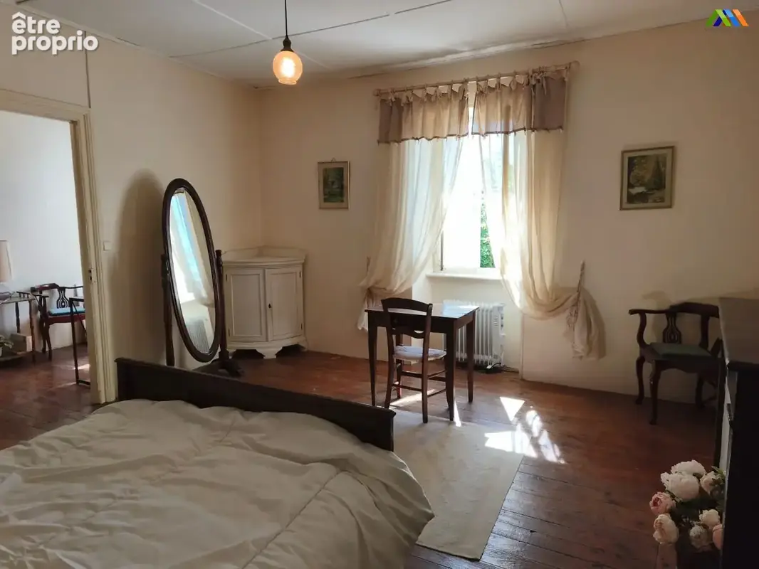 Spacious bedroom with wooden flooring, natural light and traditional French character.