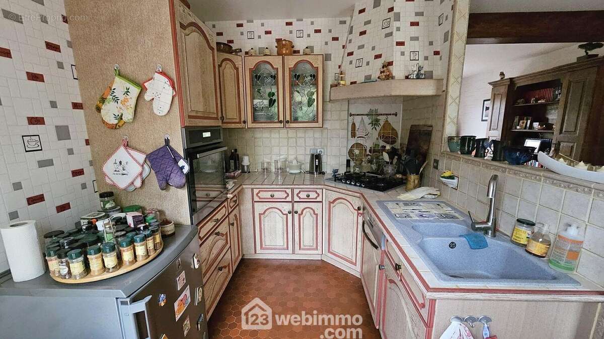 Une cuisine toute équipée avec un accès sur la terrasse. - Maison à LA FERTE-ALAIS