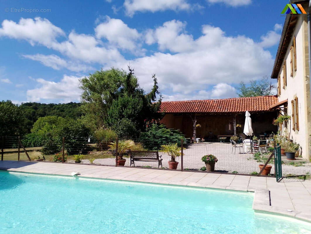 Vue dégagée sur la piscine et les dépendances de cette ferme restaurée.