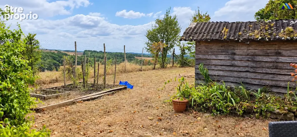 Vegetable beds and a wooden garden shed, with countryside views beyond the fence.