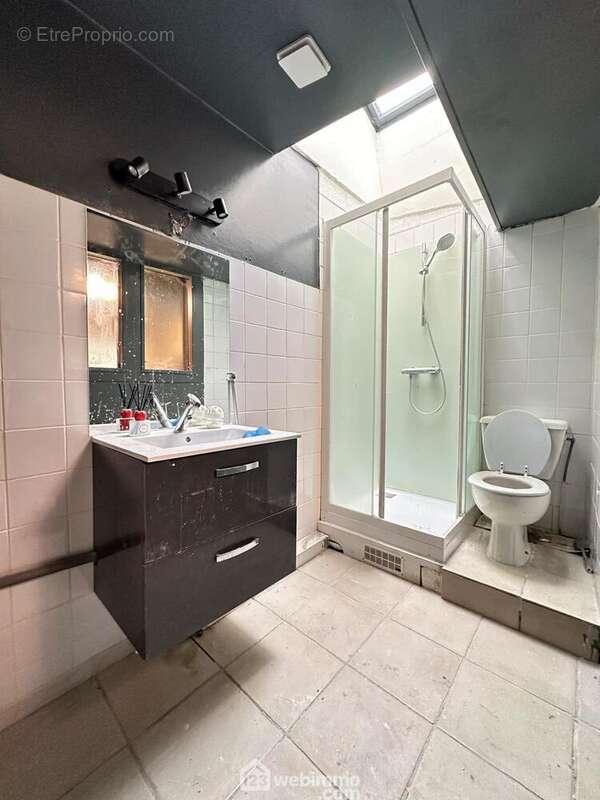 La salle de bains avec vasque sur meuble, une douche et un wc