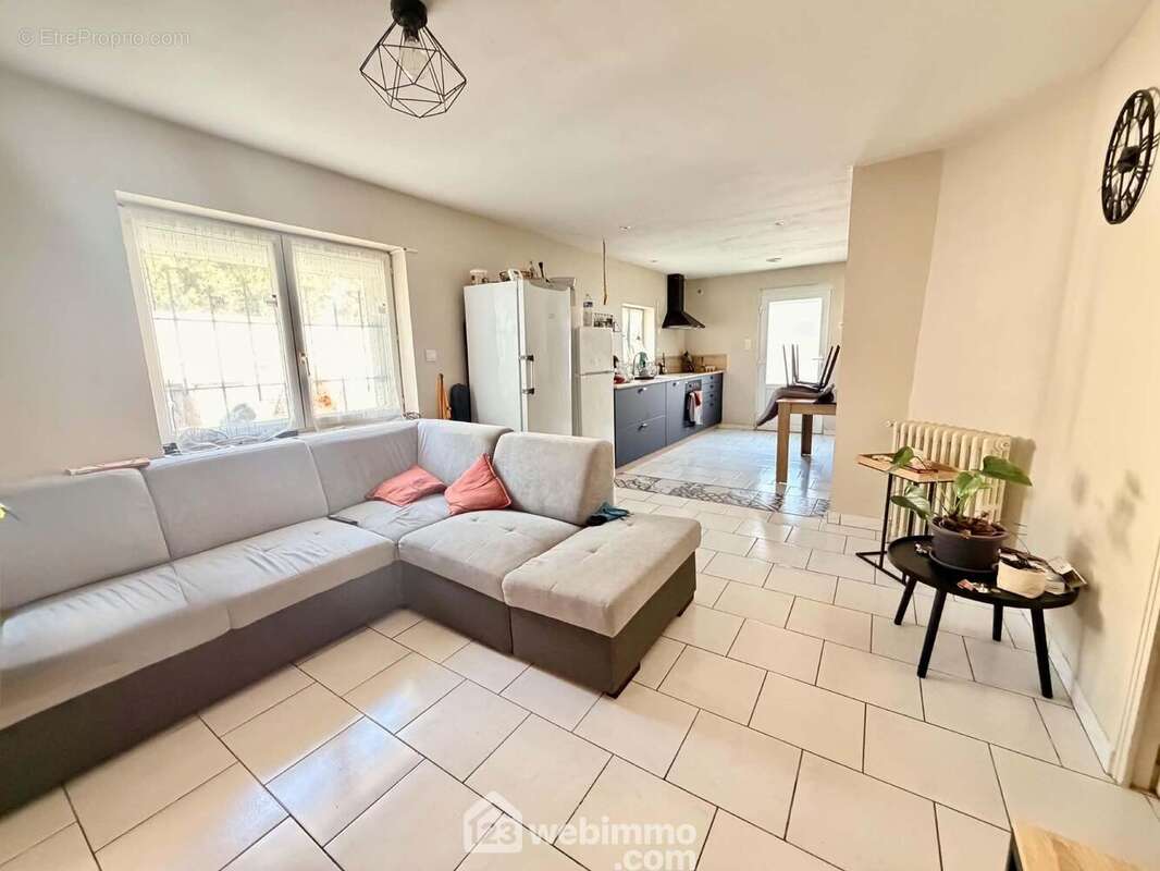 Salon lumineux bénéficiant d'une belle ouverture sur la cuisine, favorisant convivialité et partage - Appartement à MORCOURT