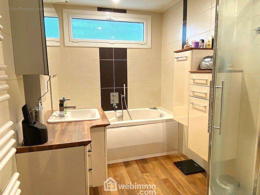 La salle de bain sur plancher teck massif de 5.28m² dispose d'une baignoire et une douche. - Maison à CHOLET