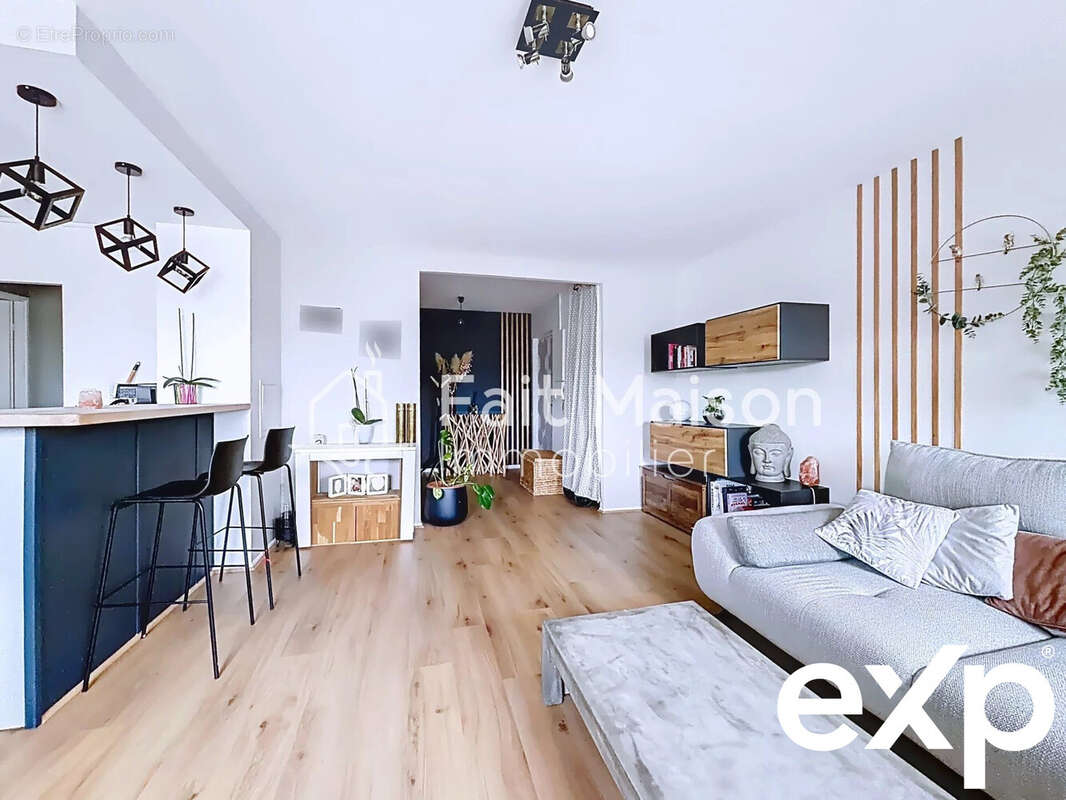 Salon moderne et lumineux avec parquet, canapé gris, bar avec tabourets et décoration contemporaine. - Appartement à MASSY