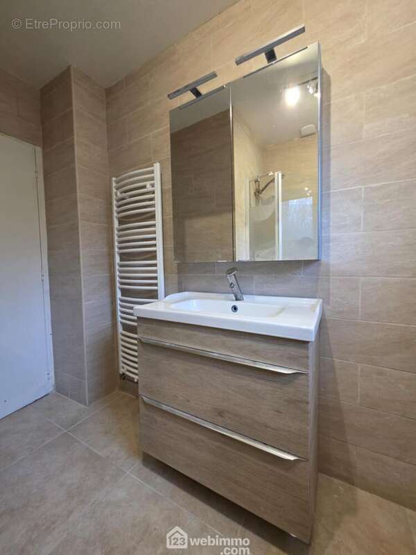 La salle de bains avec vasque sur meuble, radiateur sèche serviettes et ...