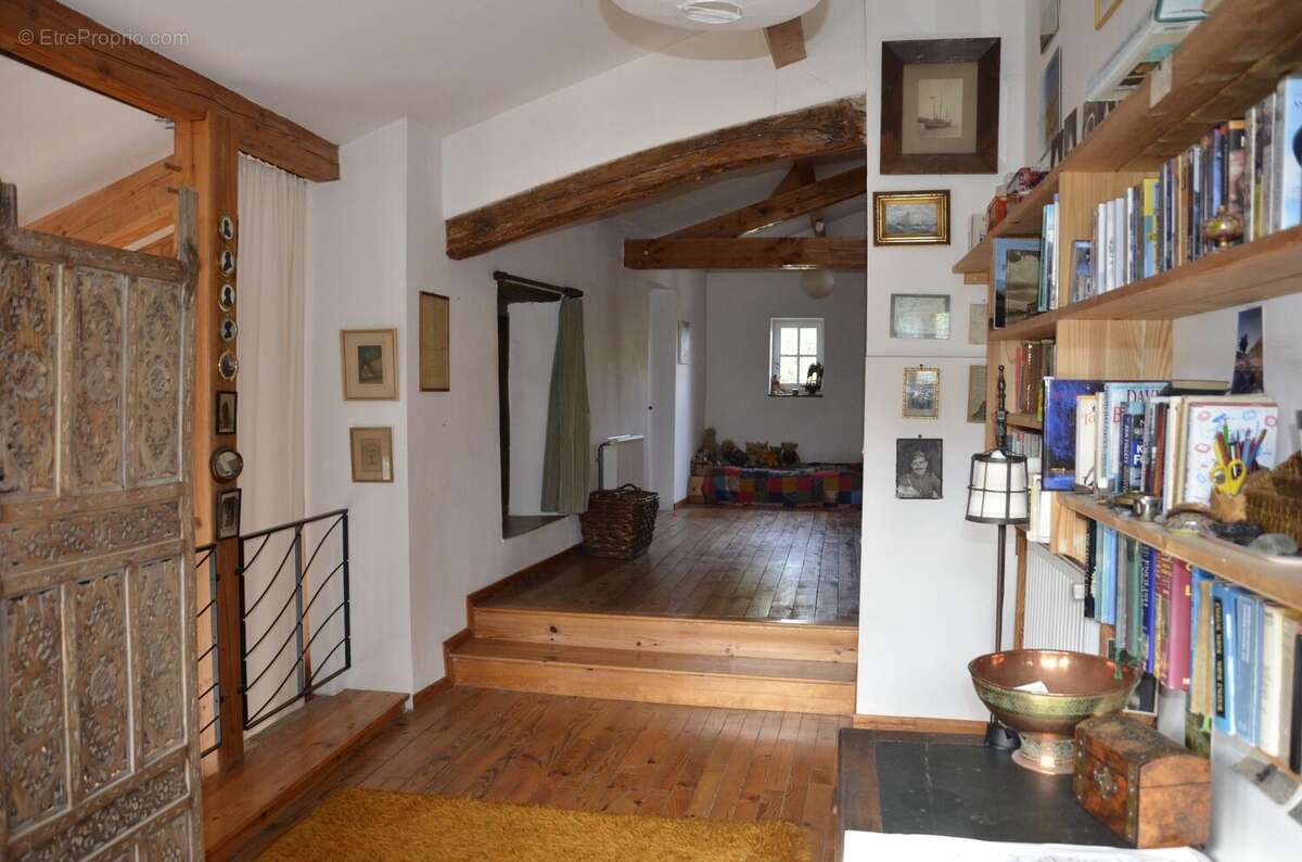 Halle intérieure avec parquet, poutres apparentes, bibliothèque et ambiance chaleureuse. - Maison à BASSOUES