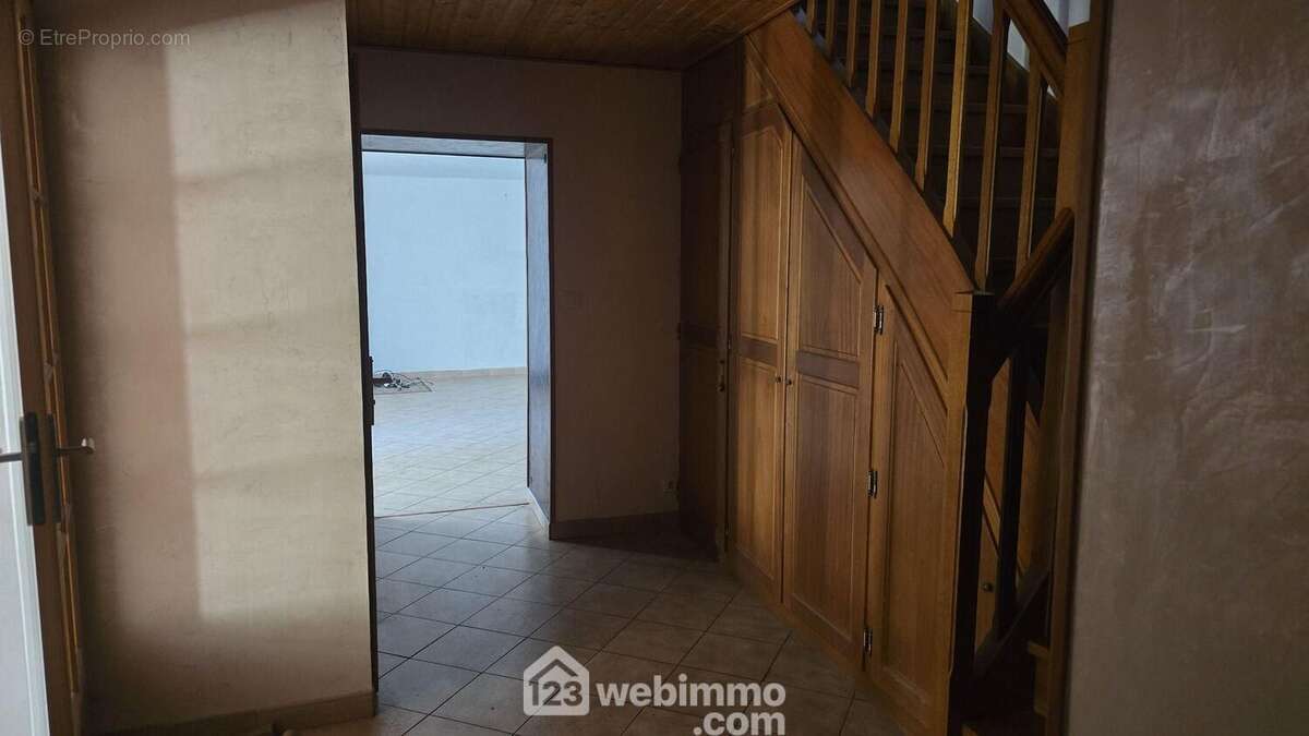 Hall d'entrée avec toilette, placards, cellier, escalier, accès cuisine et salon.