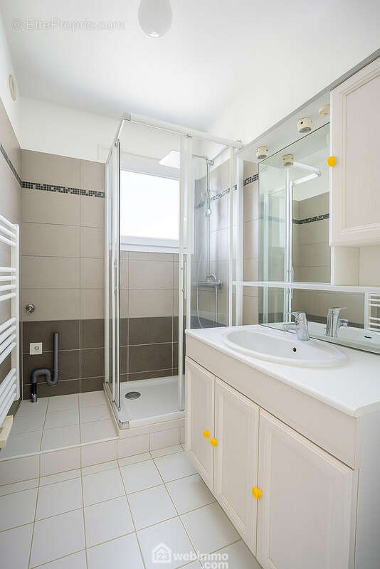 Salle d&#039;eau lumineuse avec douche vitrée, grand miroir et espace prévu pour installer une machine à laver. - Appartement à SAINTE-MAXIME