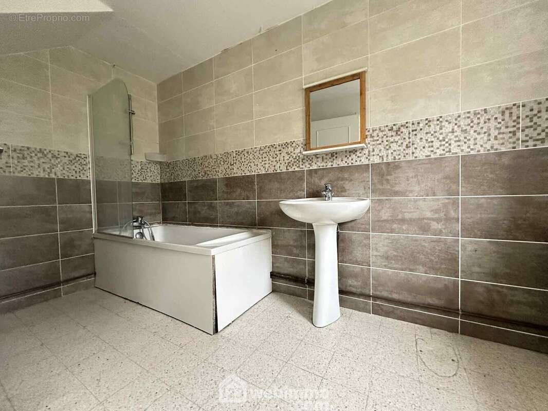 La salle de bains avec lavabo et une baignoire/douche - Maison à SISSONNE