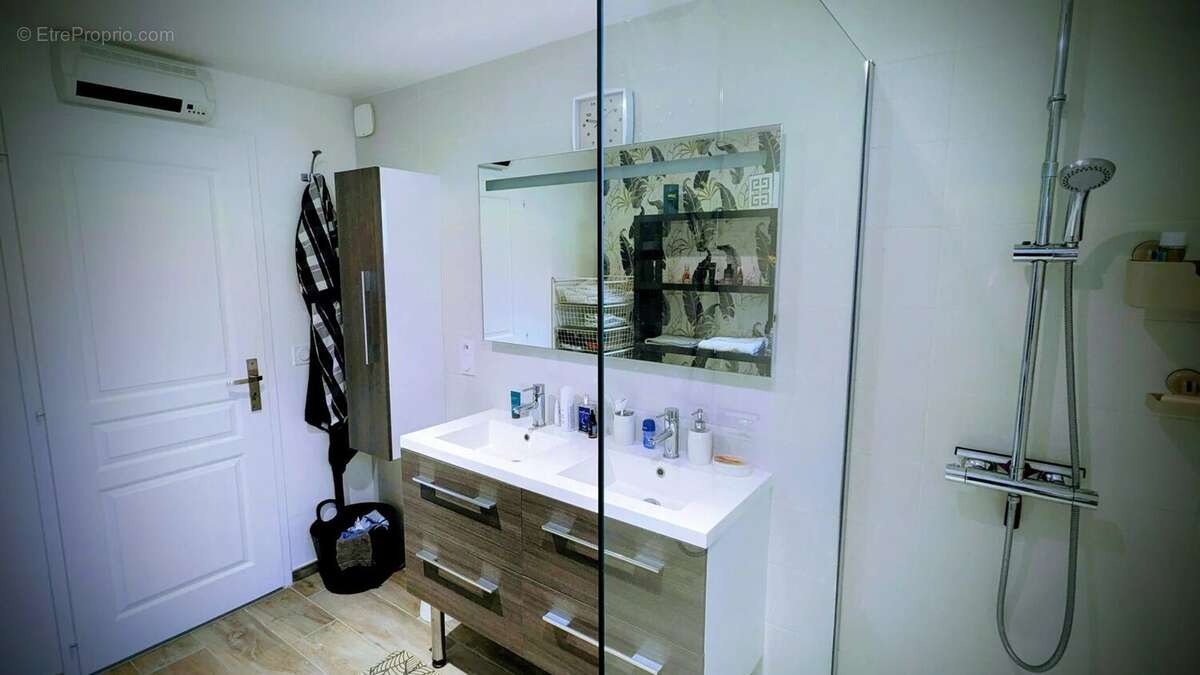 C'est une salle de bain moderne avec deux lavabos, un grand miroir, et une douche avec un design minimaliste. - Maison à AIGUILLON