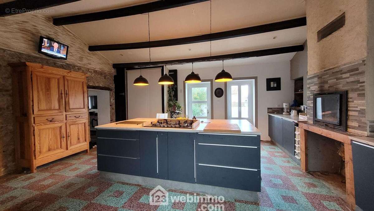 Une grande cuisine aménagée avec une cheminée insert - Maison à LE BERNARD